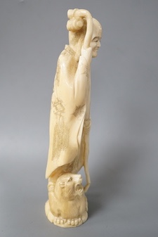 A Japanese carved walrus ivory figure of Fukurokuju, early 20th century,standing on the back of a tiger holding his staff, inset red seal mark to base, height 22cm